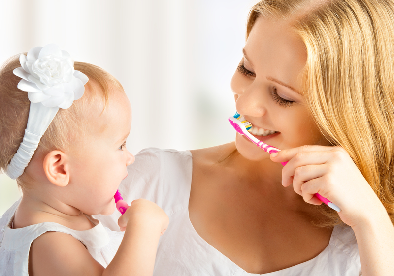 mother and daughter both brushing their teeth