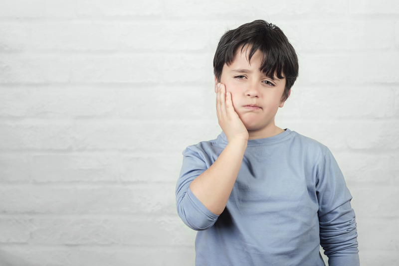 Male child with toothache holding jaw with his hand