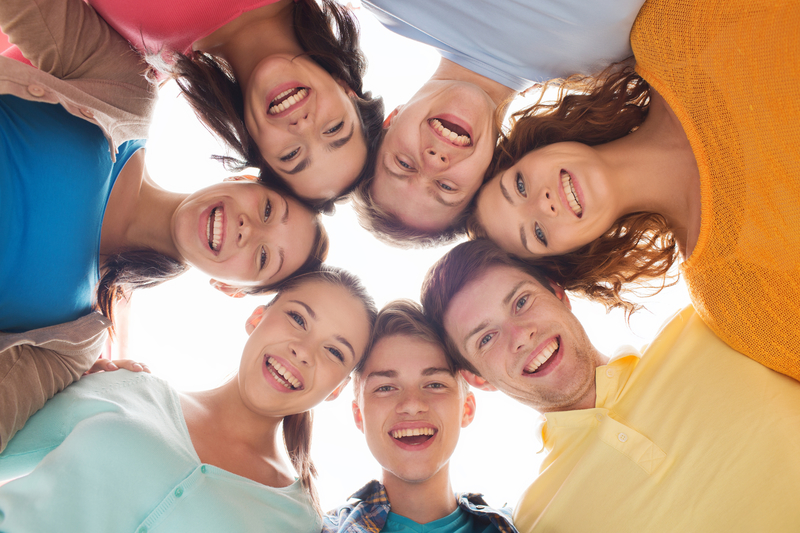 Smiling group of teenagers together in a circle looking down at the camera