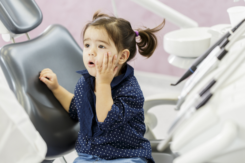 Young female child that is sitting in a dental chair with a surprised look on her face. 