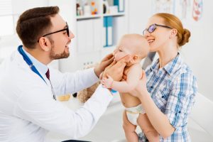 Young male infant that is having his mouth examined by a dentist.