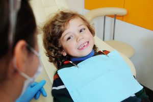 Young toddler boy that is in a dental office for a checkup and is smiling at the dental hygienist.
