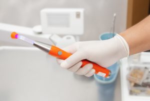 View of a hand holding a dental laser tool.