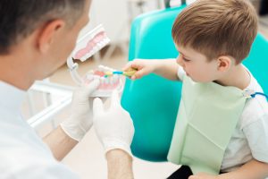 Children brushing practice teeth with dentist
