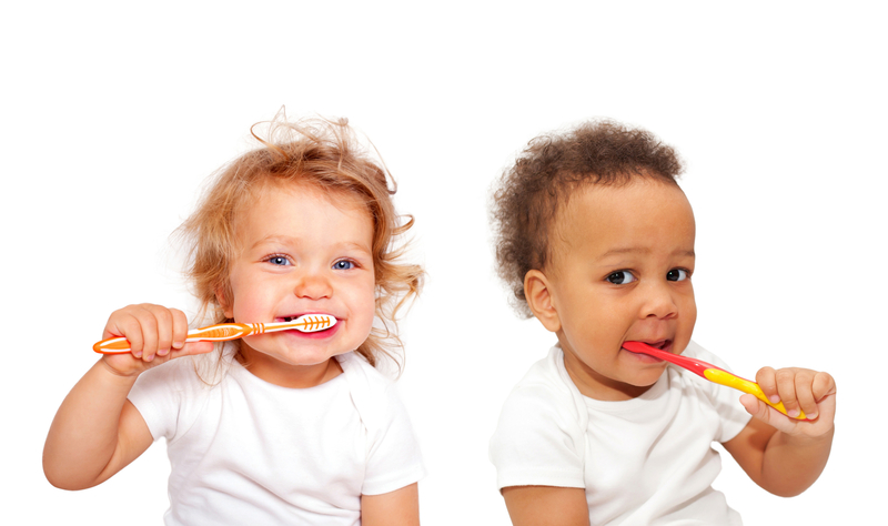 Two babies brushing teeth with toothbrushes