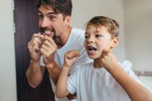 Little boy with father flossing teeth in the bathroom