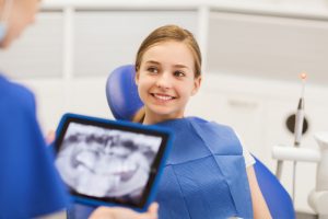 Young woman sitting in orthodontic chair looking at her dental x-rays