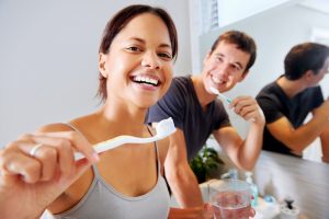 Woman and man brushing their teeth with toothpaste