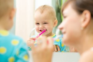 parent helping a toddler brush their teeth