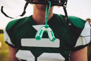 Closeup of a mouthguard hanging off of the helmet of an American football player