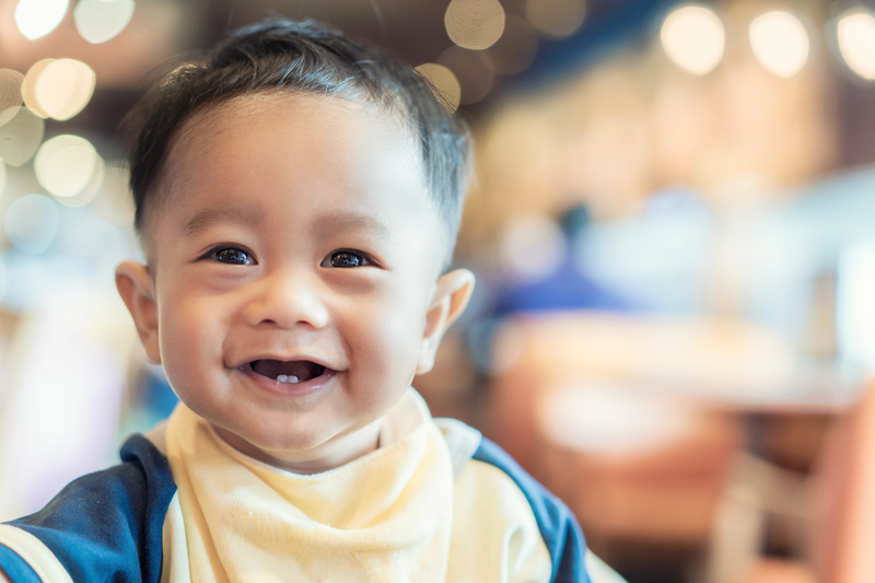 Close up of baby boy smiling with two lower teeth showing