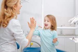 Young girl high-fiving a dental hygienist.